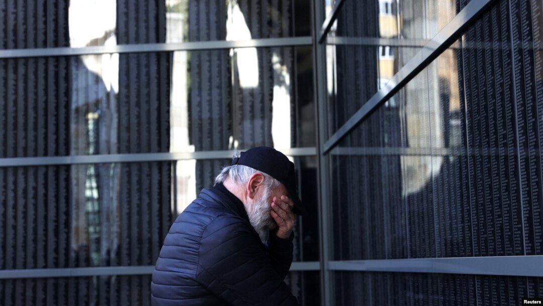A man reacts in front of a wall bearing the names of victims during a ceremony marking International Holocaust Remembrance Day at the Holocaust Memorial Center in Budapest, Hungary, Jan, 26, 2024. 
