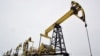 FILE - A worker walks past pump jacks at an oil field east of Izhevsk, Russia, Dec. 7, 2007. 