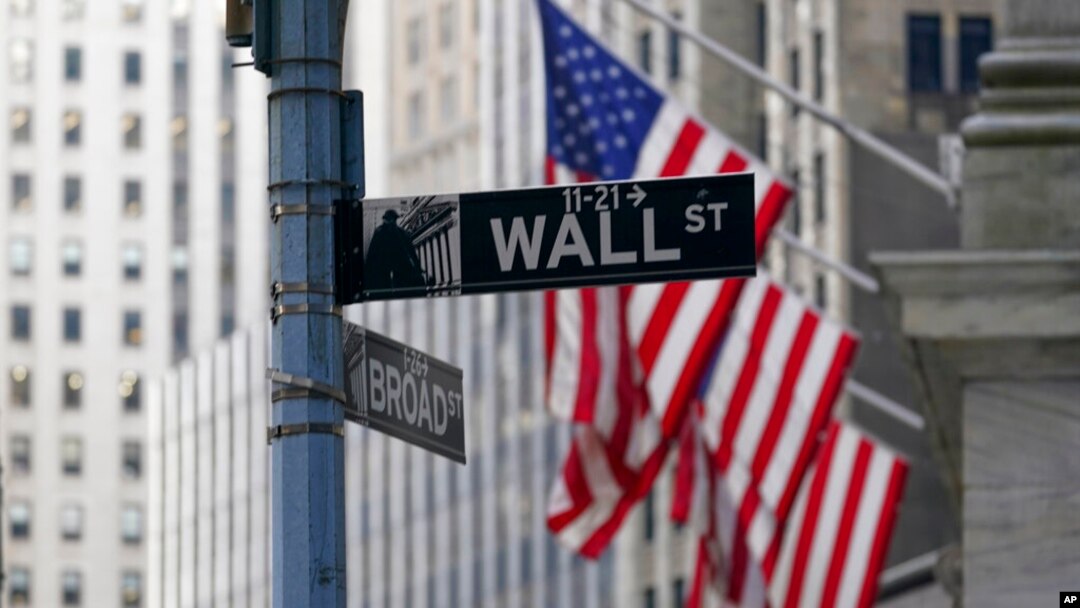 FILE - The Wall St. street sign is framed by the American flags flying outside the New York Stock exchange, Jan. 14, 2022, in the Financial District. The Dow Jones Industrial Average slumped more than 900 points April 28 as another sharp sell-off led by 