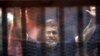 Former Egyptian President Mohamed Mursi waves as he enters for his trial with other Muslim Brotherhood members at a court in the outskirts of Cairo, May 16, 2015. 