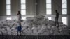 FILE - Men carry a bags of wheat to be loaded on an aid truck in a U.N. storehouse on the outskirts of Semera, Afar region, Ethiopia, May 15, 2022. 