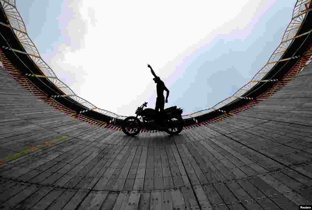 A stuntman performs a test ride on a motorcycle inside the "Well of Death" arena during a fair in Bhaktapur, Nepal.