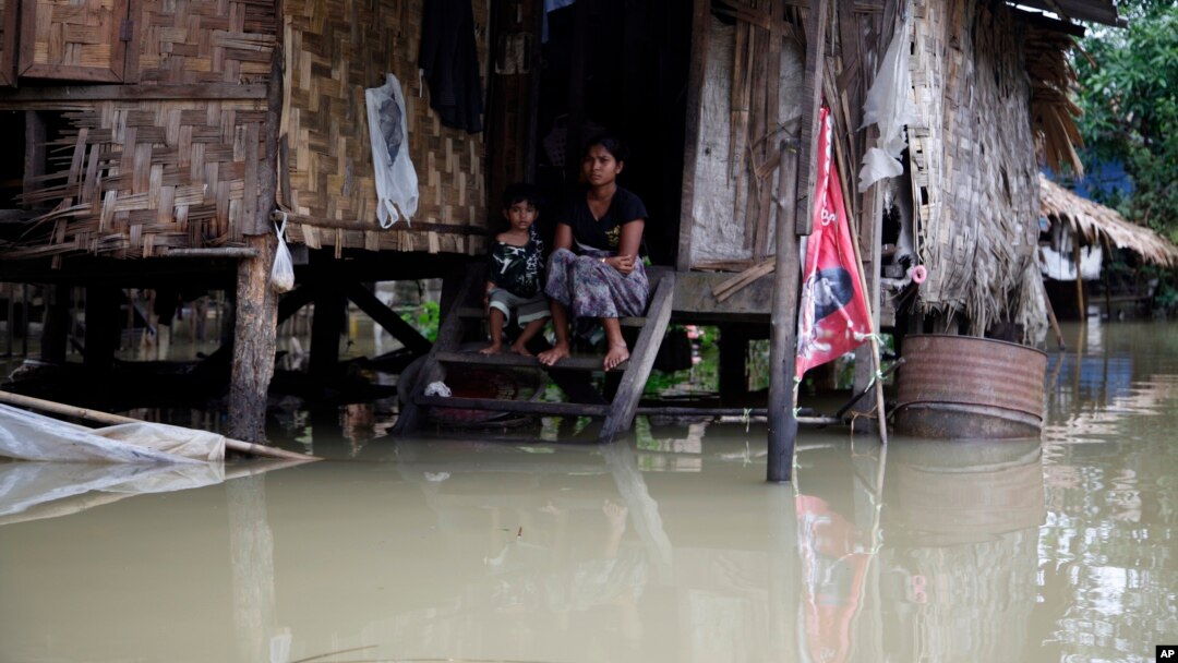 A woman and her child look out from their residence half-submerged in floodwaters in Bago, 80 kilometers northeast of Yangon, Myanmar, Saturday, Aug 1, 2015.