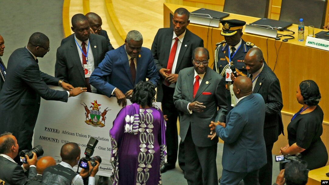 Zimbabwe's President, Robert Mugabe (C) gives a $1 million cheque to the African Union Foundation during the 29th African Union Summit in Addis Ababa, Ethiopia, July 3, 2017. 