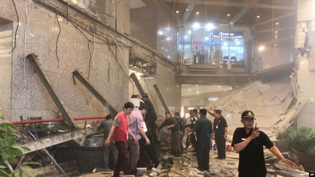 Indonesian security stand near the ruin of a structure inside the Jakarta Stock Exchange tower in Jakarta, Indonesia, Monday, Jan. 15, 2018.