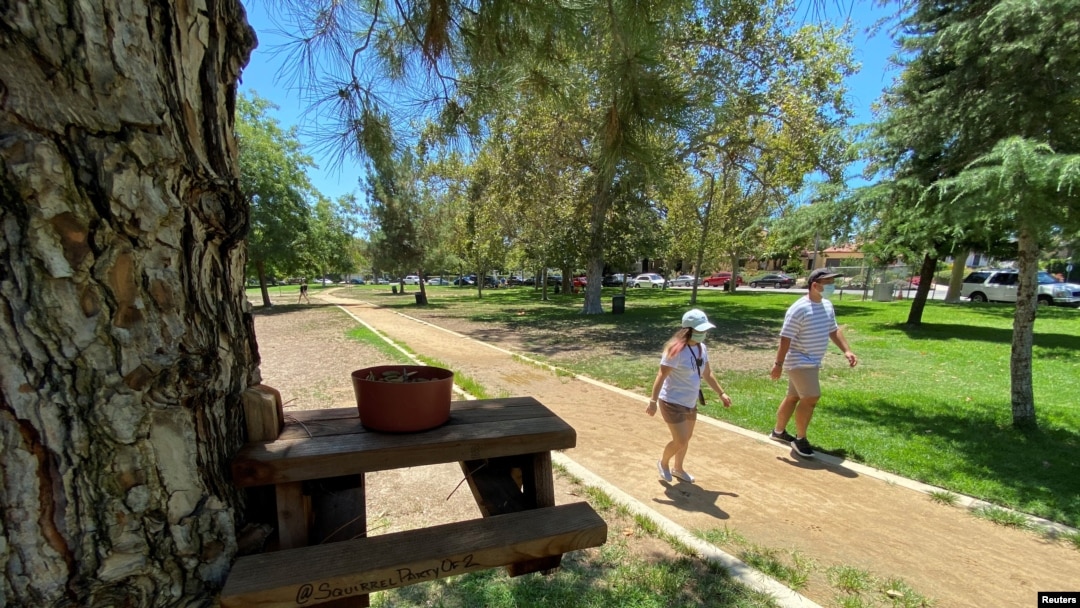 Personas usando máscaras caminan en un parque en el área de Valley Village, en Los Ángeles, California. 7 de agosto de 2020.
