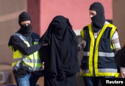 FILE - Masked Spanish police officers lead a detained woman in Melilla, Dec. 16, 2014.