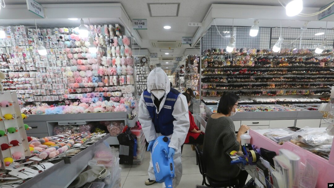 A worker wearing protective gears sprays disinfectant inside a store as a precaution against a new coronavirus at Namdaemun Market in Seoul, South Korea, Wednesday, Feb. 5, 2020. 