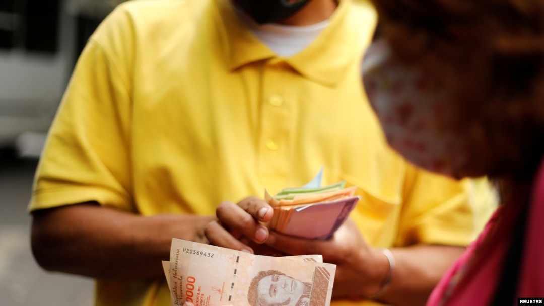 Una mujer paga un pasaje de autobús con billetes de 50.000 bolívares, la moneda local, en Caracas, el 16 de marzo de 2021. Foto: Reuters.