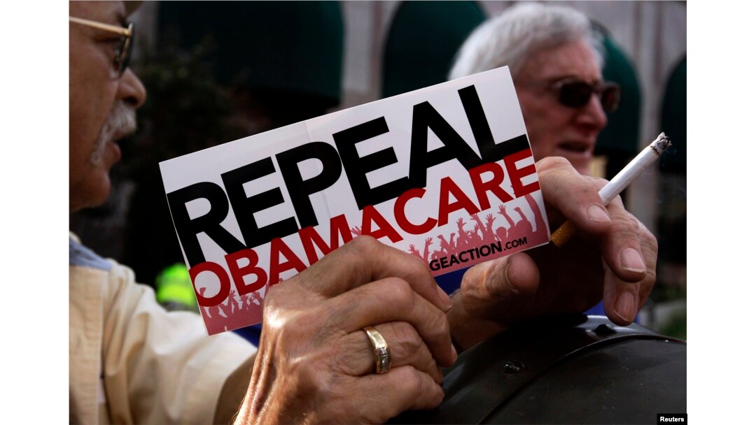 FILE - Demonstrators stand outside a hotel before former South Carolina Senator Jim DeMint, president of The Heritage Foundation, speaks at a "Defund Obamacare Tour" rally in Indianapolis, Aug. 26, 2013.