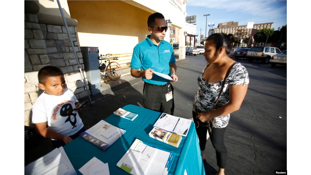 FILE - Jaime Corona, patient care coordinator at AltaMed, speaks to a woman during a community outreach on Obamacare in Los Angeles, Nov. 6, 2013.