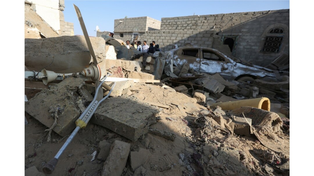 FILE - People stand at the site of a Houthi ballistic missile attack over the populated district of Rawda in Marib, Yemen, Feb. 6, 2020.