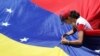 Un partidario del líder de la oposición venezolana Juan Guaidó, remienda una bandera durante una manifestación contra el gobierno del presidente Nicolás Maduro, el 6 de abril de 2019. [Foto: Reuters]