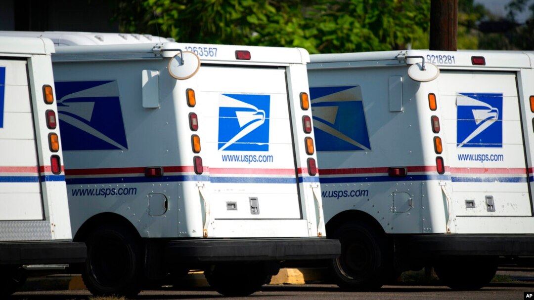 FILE - United States Postal Service delivery vans sit outside a post office in Greeley, Colo., July 26, 2021. 