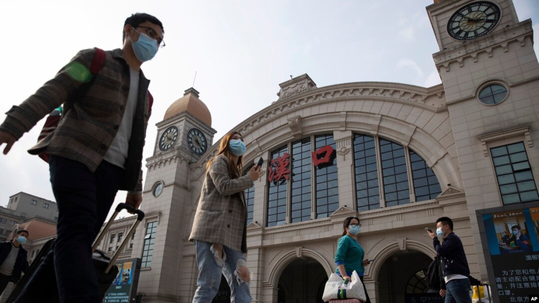 Travelers with their luggage walk past the Hankou railway station on the eve of its resuming outbound traffic in Wuhan in central China's Hubei province on April 7, 2020.