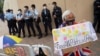 Pro-democracy supporter holds a sign calling for the release of all political prisoners outside Tin Shui Wai police station in Hong Kong, March 22, 2021.