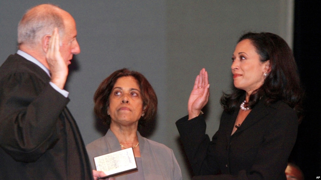 ARCHIVO - Kamala Harris con su madre, la Dra. Shyamala Gopalan, sosteniendo una copia de la Declaración de Derechos, recibe el juramento como fiscal de distrito del presidente de la Corte Suprema de California, Ronald M. George, el 8 de enero de 2004, en San Francisco.