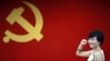 在上海的中共第一次代表大会会址，一名女子在中国共产党党旗下摆出宣誓姿势 （2012年7月1日）

