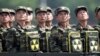 Binh sĩ Bắc Triều Tiên cầm ba lô in biểu tượng hạt nhân nhìn về phía lãnh tụ Kim Jong Un trong một buổi lễ kỷ niệm 60 năm hiệp ước đình chiến chấm dứt Chiến tranh Triều Tiên, ở Bình Nhưỡng, 27/7/2013.