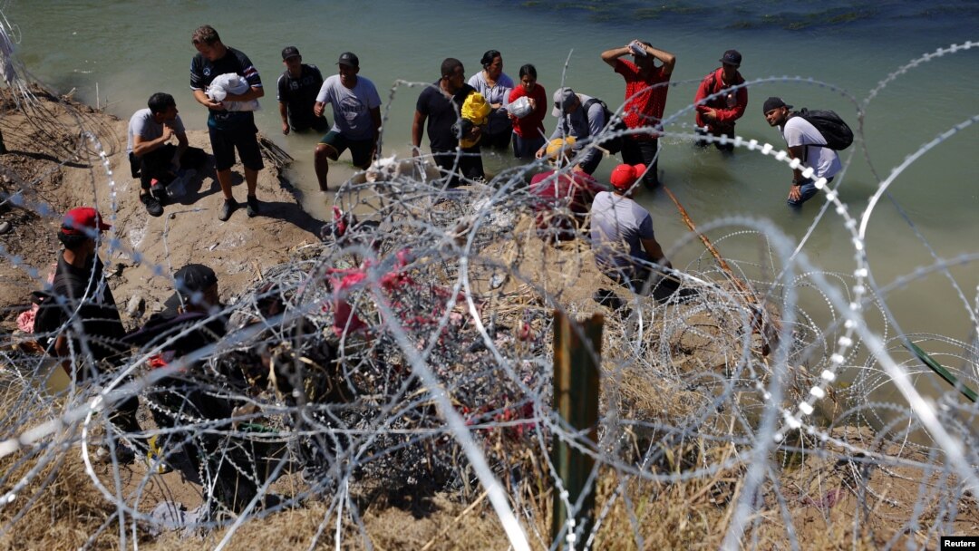 ARCHIVO - Migrantes aguardan detrás de los alambres de púas tras cruzar el Río Grande hacia Estados Unidos en Eagle Pass, Texas, EEUU, el 28 de septiembre de 2023.